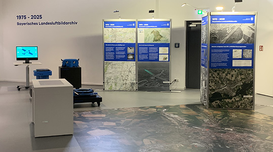Einblick in das Ausstellungsarchiv des BayLLZ. Am Boden befindet sich ein begehbares Luftbild, im Raum sind verschiedene Infotafeln.